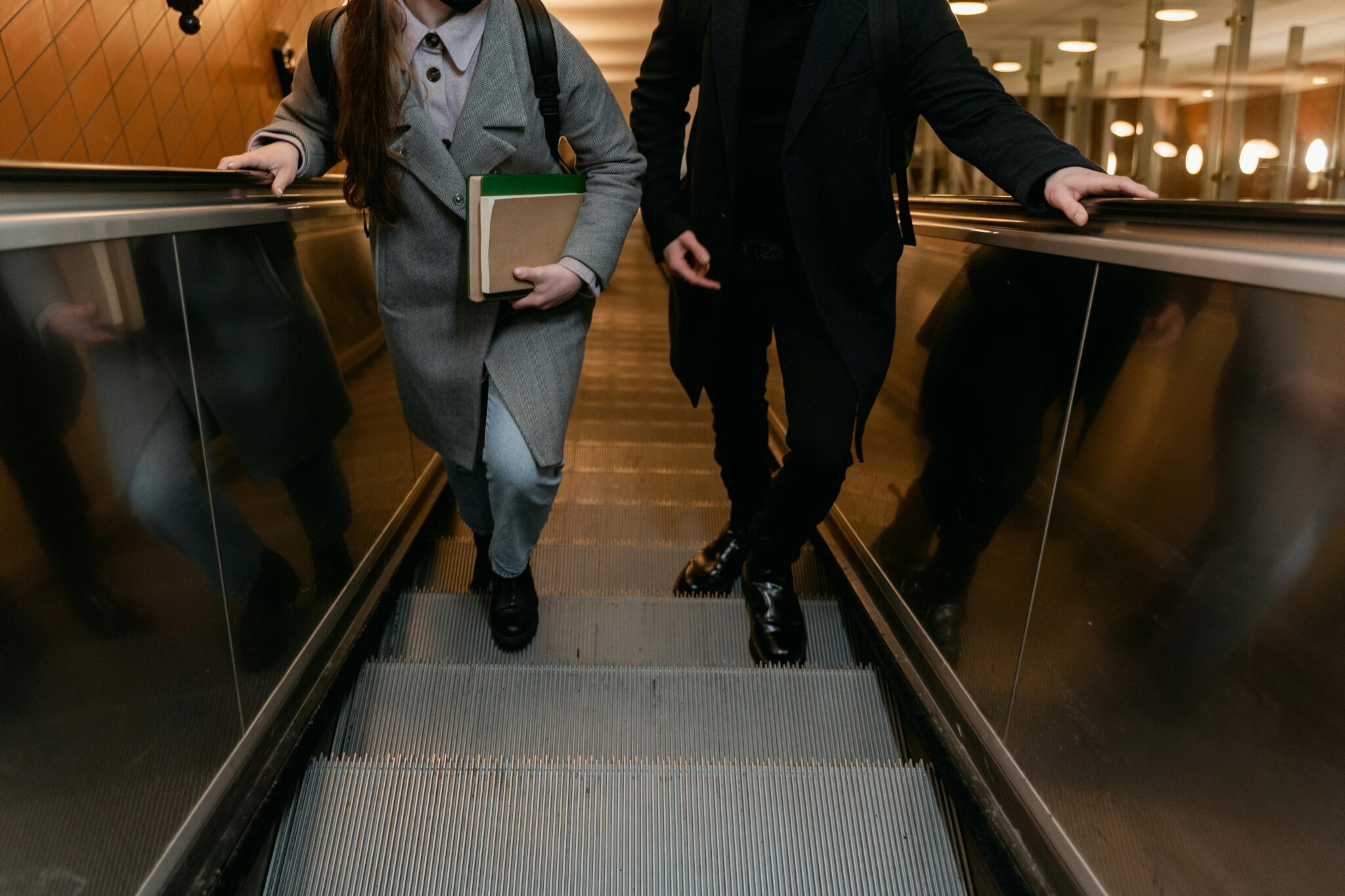 Two people on an escalator.